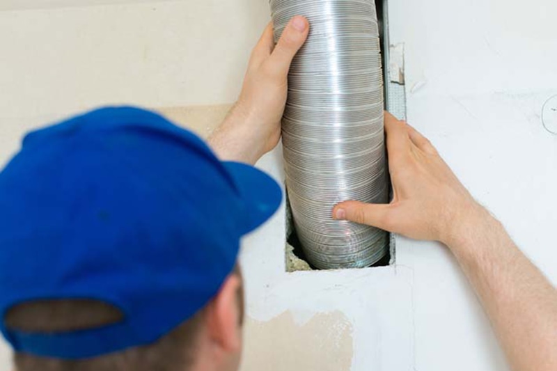 When Is It Time for a Split-System AC Replacement? Man setting up ventilation system indoors.