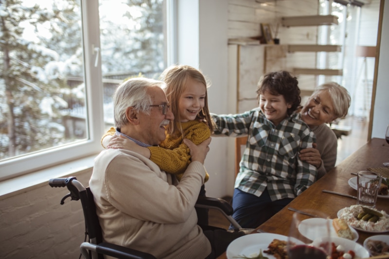 How to Lower Your Winter Heating Bill. Children laughing jumping and hugging their grandfather.