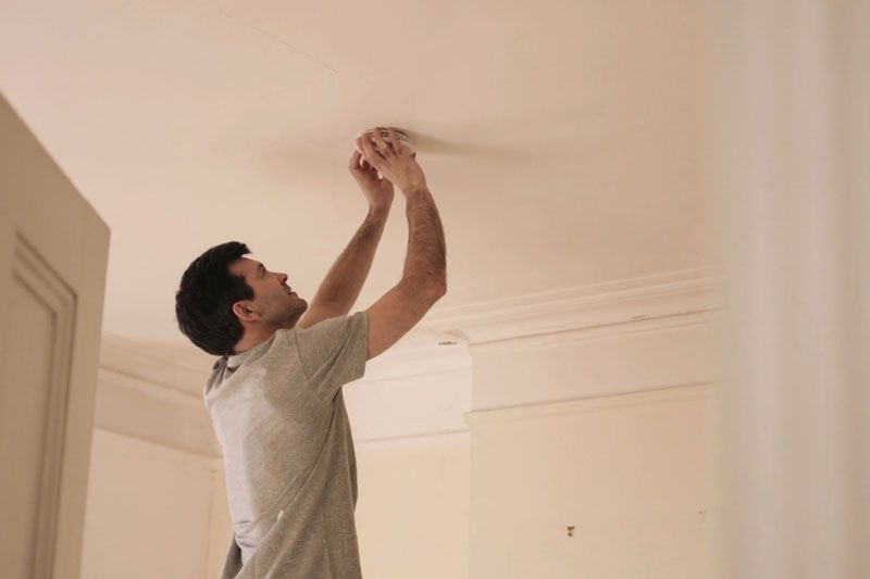 Image of someone fiddling with their smoke detector. Video - When Do I Need to Replace the Batteries in My Smoke Detector?